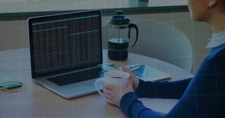 Holding white mug, woman in blue long-sleeve sweater viewing laptop terminal at home, copy space
