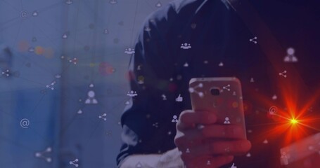 Tapping male wearing dark longsleeve shirt using phone in dim studio, social icons and lens flare