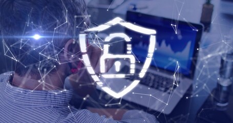 Monitoring mature man wearing striped shirt sitting at desk, viewing laptop with shield padlock