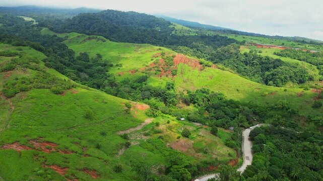 Pan‑down aerial of Quinawan Mountain View in Mariveles, Bataan, revealing rolling green hills and winding roads with scattered sunray spots lighting the forested landscape.