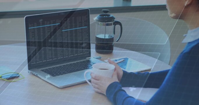Working woman in blue top holding mug, typing code on laptop at home desk, copy space