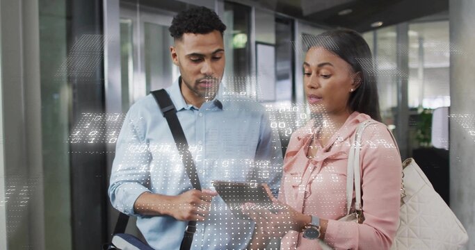 Standing colleagues in shirts examining tablet and carrying bags in office corridor, data overlay - Powered by Adobe