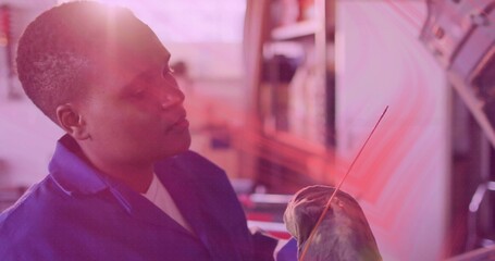 Guiding thin brush, artist in blue work coat and white shirt shaping wrapped sculpture at studio