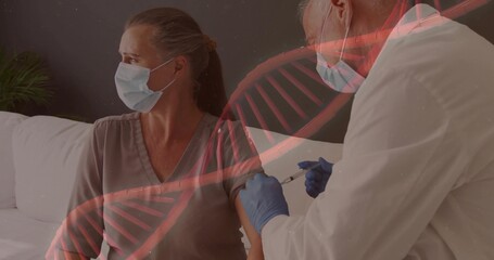 Receiving mature woman having vaccine on sofa at home, with syringe, masks, DNA overlay, copy space