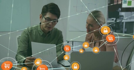 Examining document at office, man in green top explaining, woman in light top viewing laptop, icons