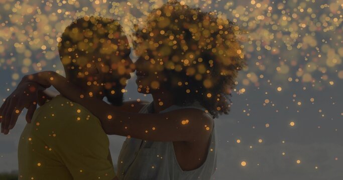 Embracing couple holding close at beach at dusk, with yellow shirt sleeveless top and golden bokeh - Powered by Adobe