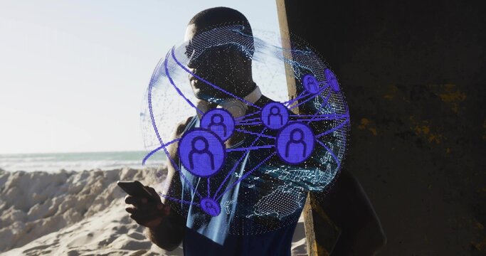 Holding phone, man standing at beach near pier, in blue tank, headset, showing network hologram