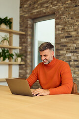 Professional Man Working on Laptop in Modern Office with Brick Wall and Green Plants