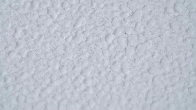 Textured, monochromatic, close-up view showing a white, irregular surface with a network of cracks