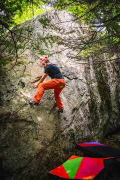 A male rock climber looking for a foot hold on a bouldering problem