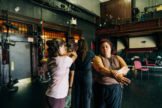 Three people in discussion during rehearsal on a dark stage