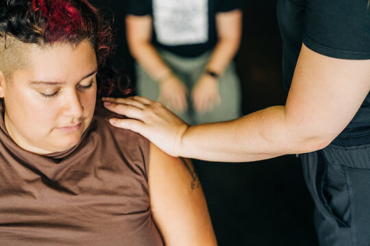 Person receives comforting hand on shoulder during quiet moment