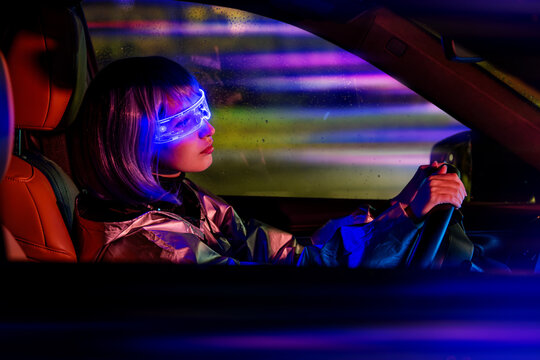 young woman driving car at night wearing futuristic AR glasses