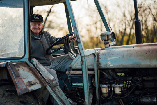 Elderly man smiles while driving his vintage tractor