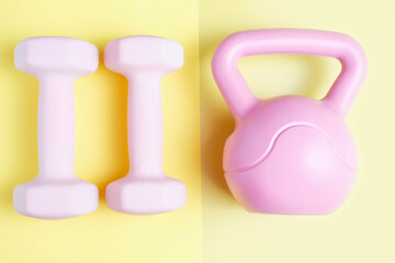 Kettlebell and dumbbells on yellow background close-up top view.