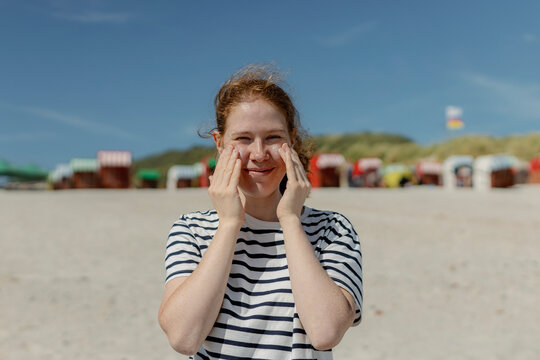 Redhead applying sun cream on beach at Helgoland North Sea Germany