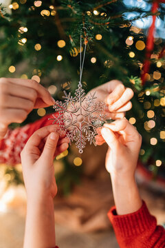 Hands decorating Christmas tree with silver snowflake ornament