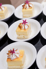 Individual mini lemon dessert squares with toasted meringue, red purple petal, served in small white ceramic tasting dishes