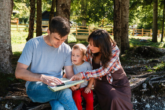 Family using map for exploration in forest on outdoor adventure