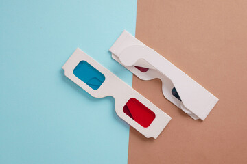 Two pairs of retro cardboard anaglyph 3D glasses on a beige brown background. Top view