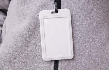 Blank white id badge hanging on the neck of a woman in a sports fleece sweatshirt. Trainer, gym instructor, sports and fitness concept. Design mockup.