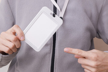 Blank white id badge hanging on the neck of a woman in a sports fleece sweatshirt. Trainer, gym instructor, sports and fitness concept. Design mockup.