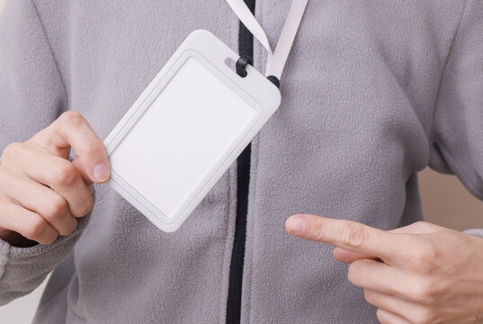 Blank white id badge hanging on the neck of a woman in a sports fleece sweatshirt. Trainer, gym instructor, sports and fitness concept. Design mockup.
