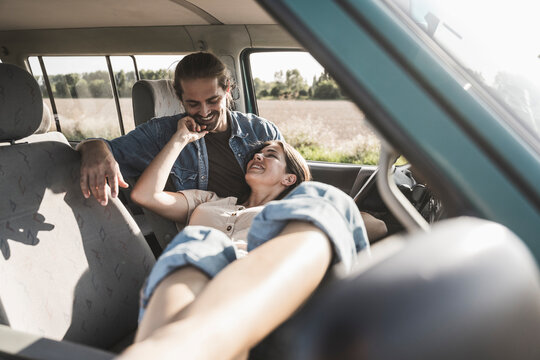 Happy young couple spending time together in van on sunny day