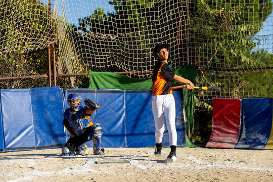 Young baseball player batter swinging with catcher