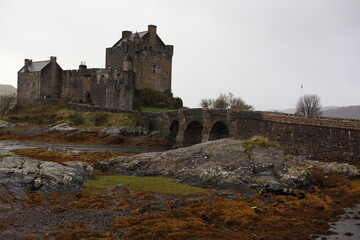 Eilean Donan Castle in Scotland, a historic medieval fortress perched on island, connected by a stone bridge and surrounded by scenic loch and hills.