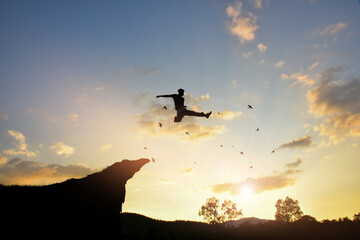 Man jumping over precipice between two rocky mountains