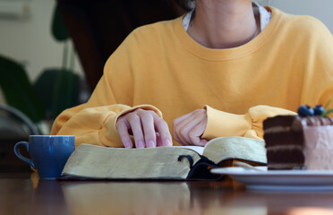 woman hands on bible. she is reading and praying over bible over wooden table