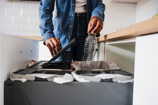 Young woman recycling plastic bottles in kitchen at home - Powered by Adobe