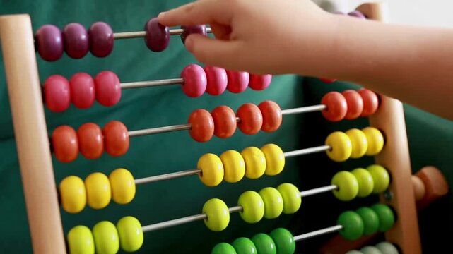 Childs hand moving colorful beads on a classic wooden abacus