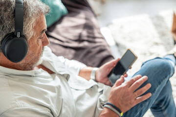 Senior man relaxing at home listening to music