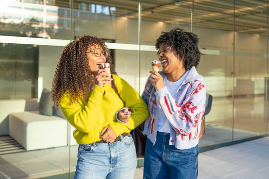 Happy young women friends laughing eating ice cream