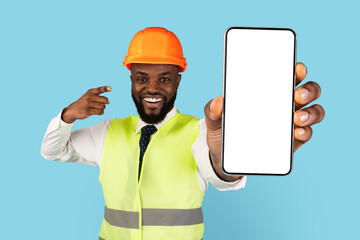 Happy African American Construction Worker Pointing At Blank Smartphone In Hand, Handsome Smiling Black Man Wearing Hard Hat And Safety Vest Demonstrating Copy Space For Mockup, Creative Collage