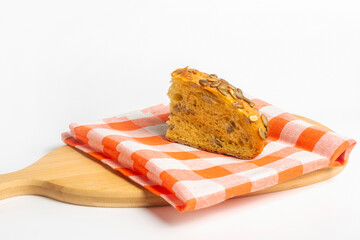 A slice of pumpkin bread with seeds on a cutting board. Healthy food