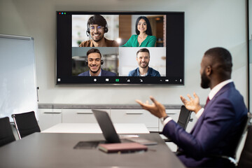 African american businessman having video conference with multiracial team employees, looking at digital display, talking, gesturing. Colllage for modern technologies and business concept