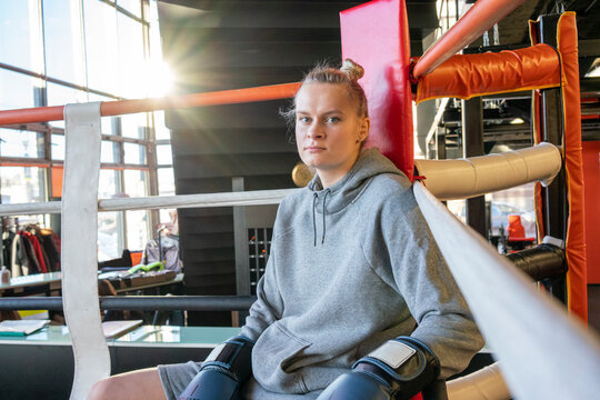 Portrait of a female boxer in gym sitting in ring corner