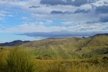 Fototapeta premium Danseys Pass Kakanui Range tussock-covered high country mountains in springtime under a blue cloudy sky. Waitaki and Central Otago in the South Island of New Zealand.
