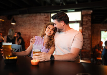 Couple drinking beer and eating snacks in a pub