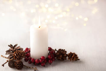 Advent candle and lights of garland  on white rustic wooden table.  Selective focus.