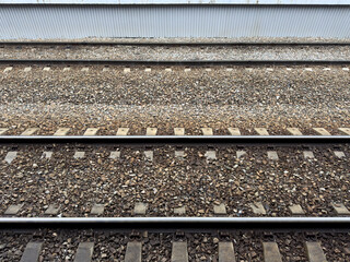 Railroad tracks covered with crushed stone. View from the platform onto the tracks for arriving trains at the station. Concept of railroads as means of transporting people and goods