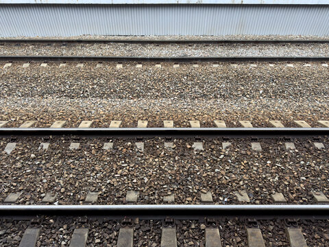 Railroad tracks covered with crushed stone. View from the platform onto the tracks for arriving trains at the station. Concept of railroads as means of transporting people and goods