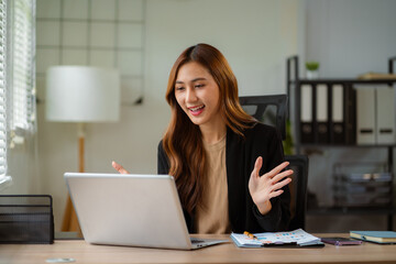 
Asian businesswoman presenting ideas and analyzing financial charts during an online meeting.