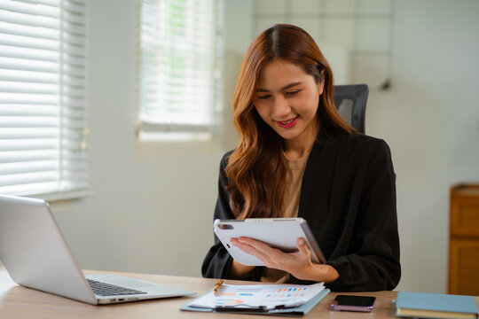 Business women hand working with tablet and laptop computer with documents on office desk in modern office. - Powered by Adobe