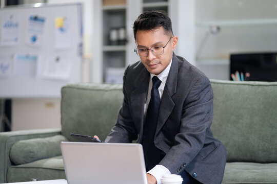 Businessman using smartphone and laptop computer in office. Happy man, entrepreneur, small business owner working online. - Powered by Adobe