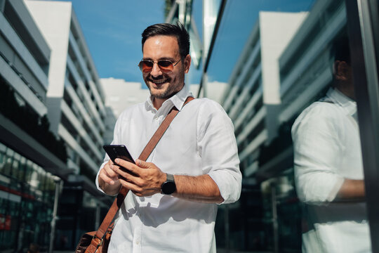 Young professional smiling, using smartphone in city