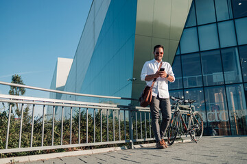 Young man commuting to work using smartphone and bicycle